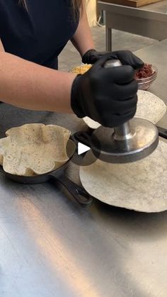 a woman in black gloves is making tortillas