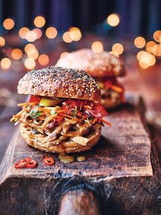 two burgers sitting on top of a wooden cutting board