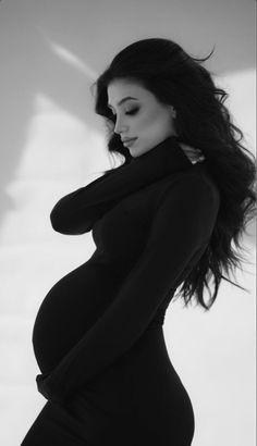 a pregnant woman poses for a black and white photo with her hands on her hips