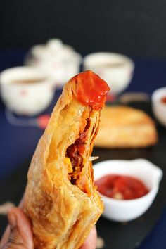 a person holding up a piece of food with ketchup on top of it