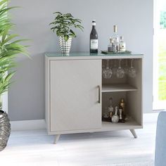 a small cabinet with wine glasses and bottles on the top, next to a potted plant