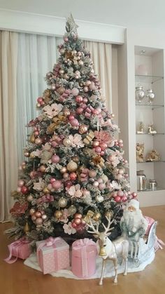 a decorated christmas tree in a living room with pink and gold ornaments on the top