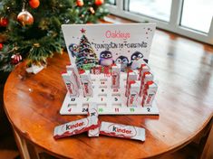 a wooden table topped with candy bars next to a christmas tree and a calendar on it