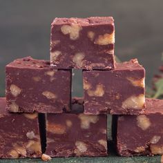 several pieces of fudge chocolate stacked on top of each other with walnuts in the background