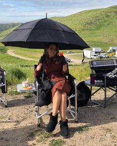 a woman sitting in a chair with an umbrella over her head