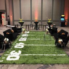 an artificial football field is set up for a wedding reception with black chairs and white flowers