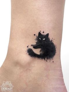 a black cat tattoo on the ankle with ink splatters all over it's body