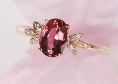 a pink diamond ring sitting on top of a flower