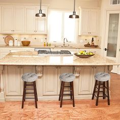 a large kitchen island with stools in front of it and an oven on the other side