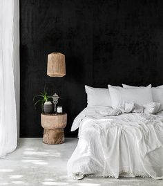 a bedroom with black walls and white bedding