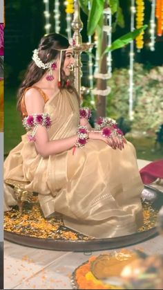 a woman sitting on the ground with flowers in her hair and jewelry around her neck