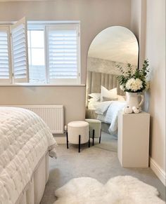 a bedroom with a bed, mirror and white furniture