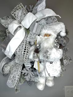 a white christmas wreath with santa claus and other decorations on it's front door