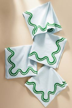 three napkins with green and white designs on them sitting on top of each other