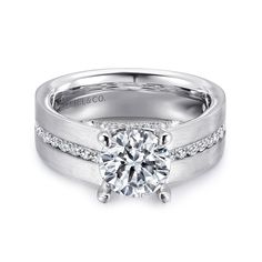 a white gold engagement ring set with diamonds on the side and an accent diamond in the center