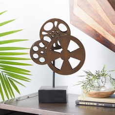 a metal sculpture sitting on top of a table next to a potted palm tree