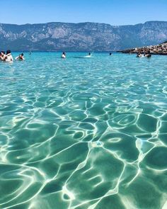 people are swimming in the clear blue water