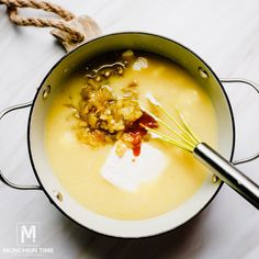 a pot filled with soup sitting on top of a white counter next to a wooden spoon