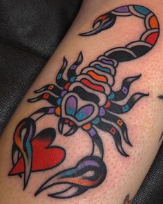 a colorful scorpion tattoo on the left arm and leg, with hearts in the center