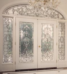 an ornate glass front door with chandelier