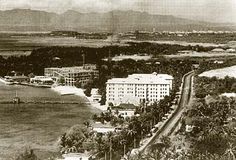 an old black and white photo of a city with mountains in the backgroud