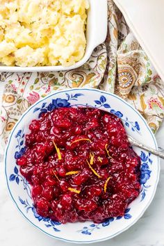 a bowl filled with cranberry sauce next to a casserole dish full of mashed potatoes