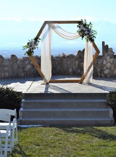 an outdoor ceremony setup with white flowers and greenery on the steps leading up to it