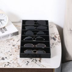 a pair of black sunglasses sitting on top of a marble table next to a clock