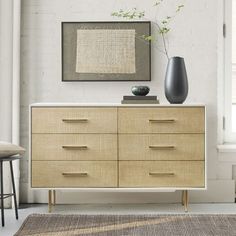 a modern dresser with two vases on top and a painting hanging above the drawers