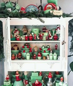 a china cabinet filled with lots of green dishes and christmas decorations on top of it