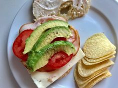 a sandwich with avocado, tomato and lettuce is on a plate