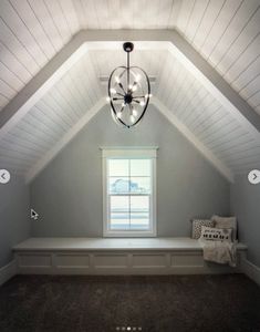 a room with a window, bench and light fixture in the middle of it's ceiling