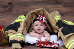 a baby girl with a firetruck on top of her diaper in front of some fire hoses