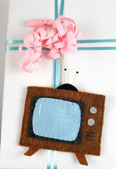 a brown and blue tv sitting on top of a white box with pink ribbon around it