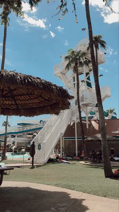 an umbrella and some palm trees in front of a building with stairs leading up to it