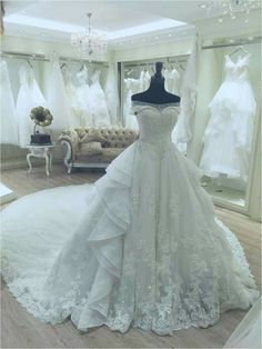 a white wedding dress on display in a room filled with mannequins and dresses