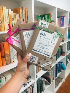 someone is holding up some books in front of a book shelf