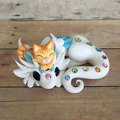 a cat figurine sitting on top of a wooden floor next to a white dragon