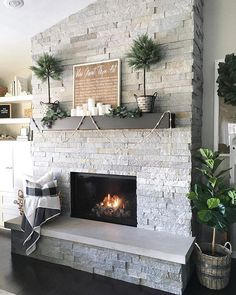 a living room with a white brick fireplace and potted plants on the mantel