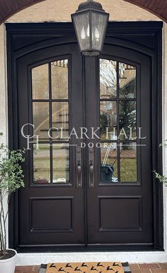 a black double door with two sidelights and a welcome mat in front of it