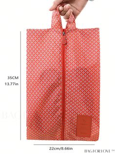 a person is holding an orange bag with red zippers and the measurements are shown