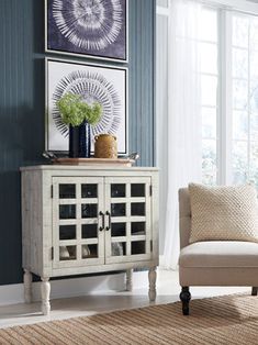 a living room scene with focus on the chair and sideboard in front of the window