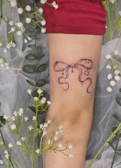 a woman's foot with a tattoo on it and flowers in the foreground