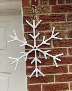 a white snowflake hanging from the side of a brick building