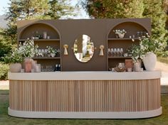 an outdoor bar with mirrors and vases on the shelves, decorated with white flowers