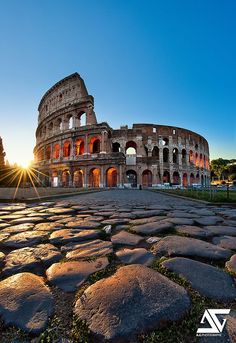 the colossion in rome, italy at sunset with bright sun rays coming through