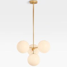 three white glass balls hang from a brass - plated chandelier