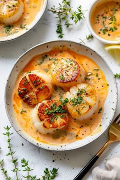 two bowls filled with soup and garnished with scallops on the side