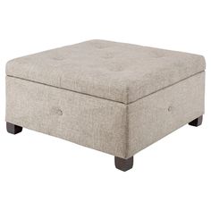 a beige ottoman with wooden legs and buttons on the footrests is shown in front of a white background