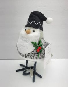 a small white bird with a black hat and scarf on it's head sitting in a box